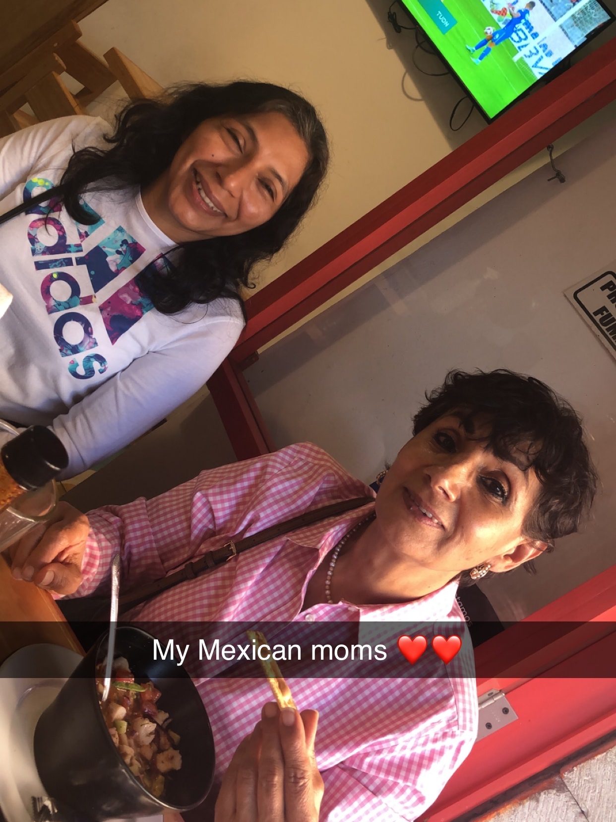 Two women smile at the camera in a Mexican restaurant.