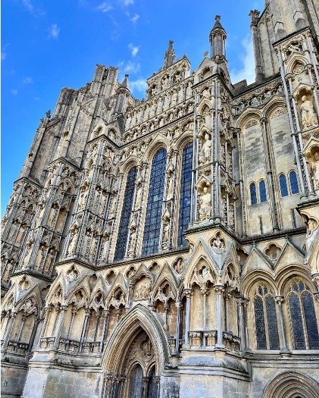 The outside of the Wells Cathedral is ornate and covered in old sculptures.