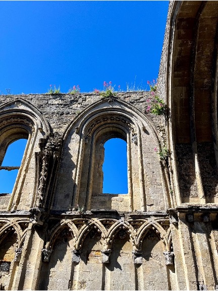 Details arches of the Glastonbury Abbey are topped with bright pink flowers.