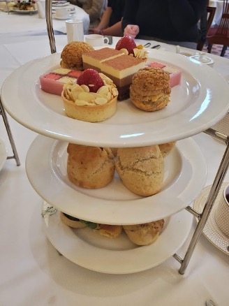 A three-tiered tray holds sandwiches, scones, and desserts.